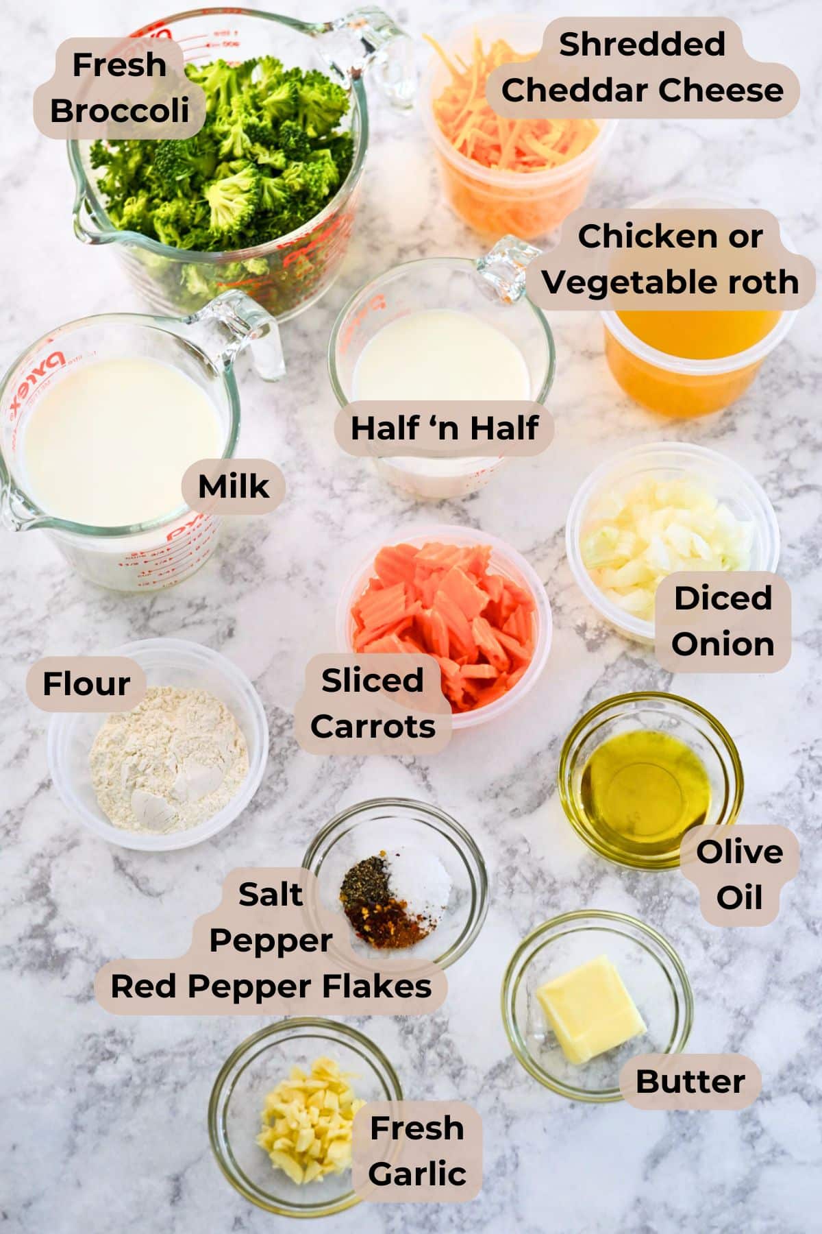 Measured ingredients for a Broccoli Cheese Soup recipe arranged on a marble surface, each labeled by name, ready for easy preparation.