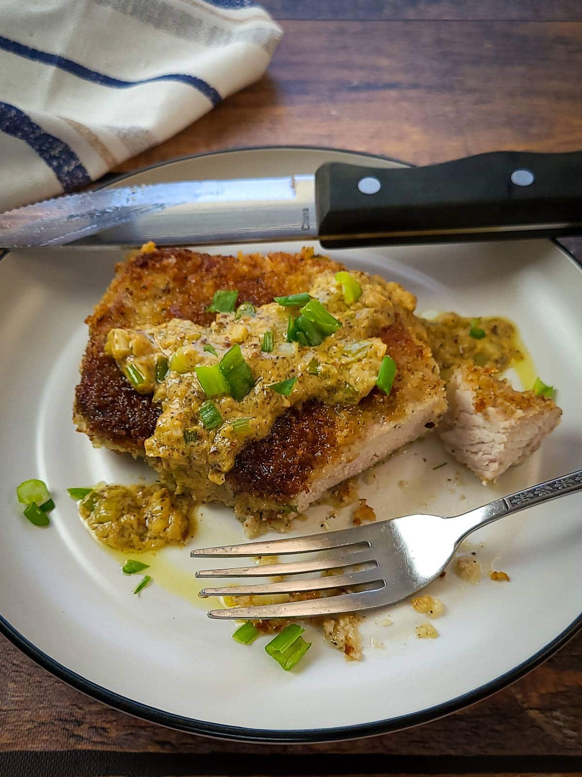 a panko pork chop on a plate with a knife and fork