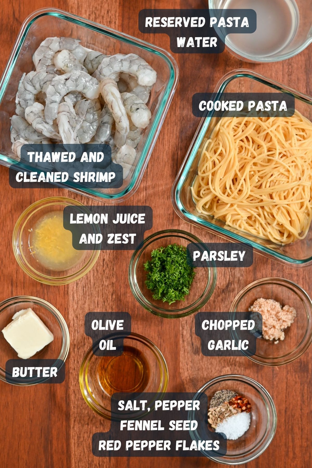 Assorted ingredients for Lemon Shrimp Spaghetti recipe neatly arranged on a wooden surface.