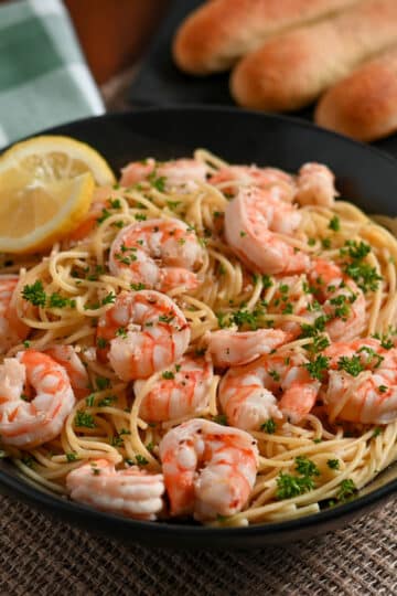 A bowl of Lemon Shrimp Spaghetti garnished with parsley and a slice of lemon.