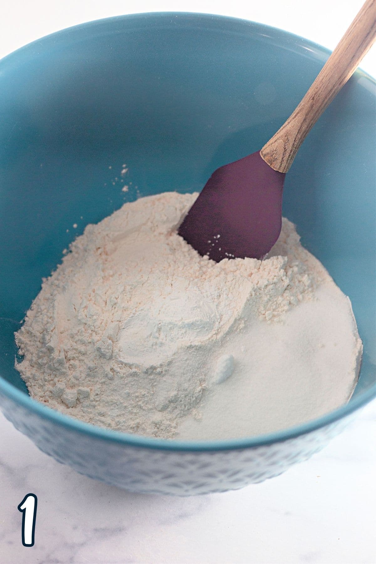Flour, baking powder, and salt in a blue mixing bowl. 