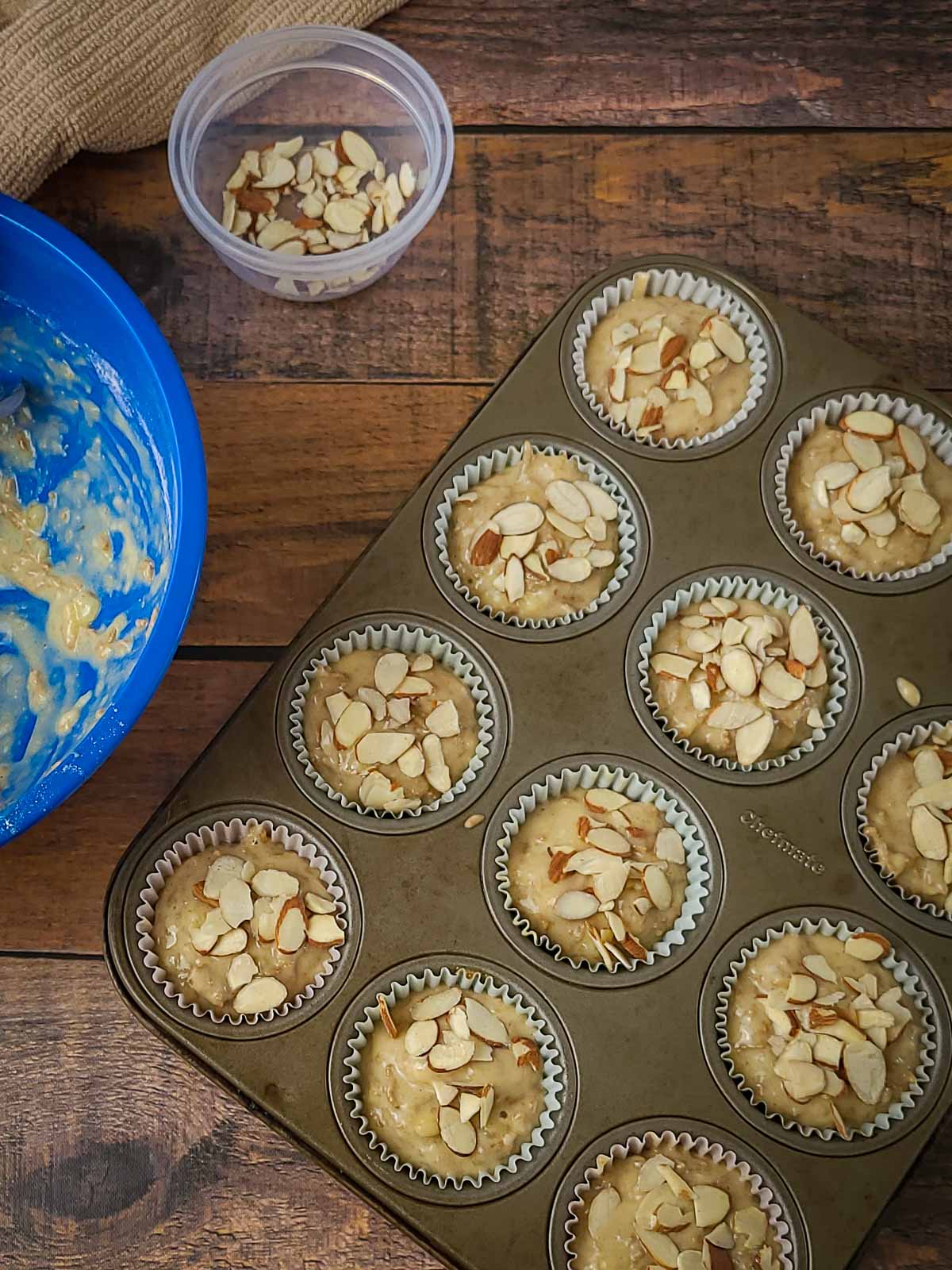 muffin batter in a muffin pan topped with almonds