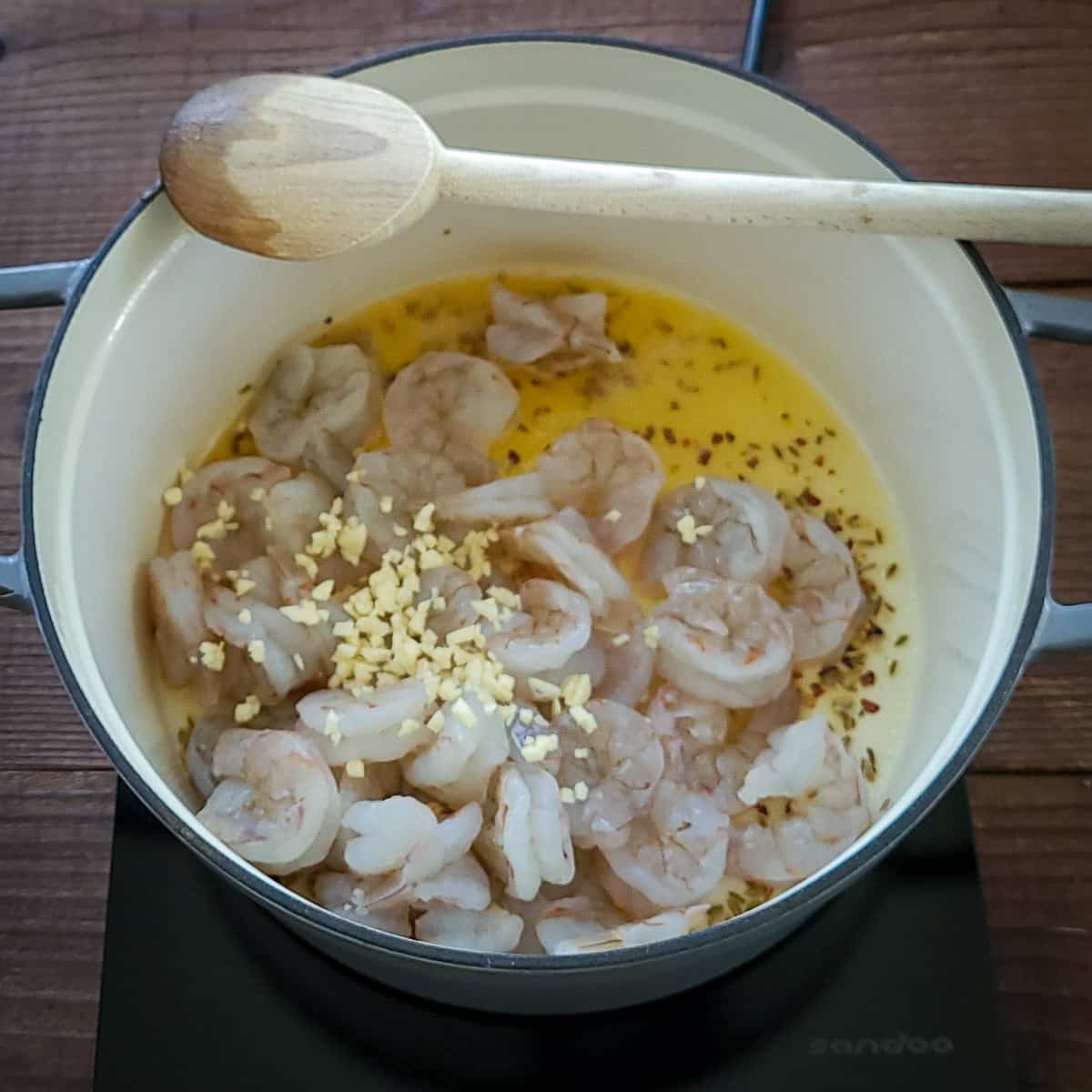 a large pot cooking shrimp with garlic in olive oil and butter