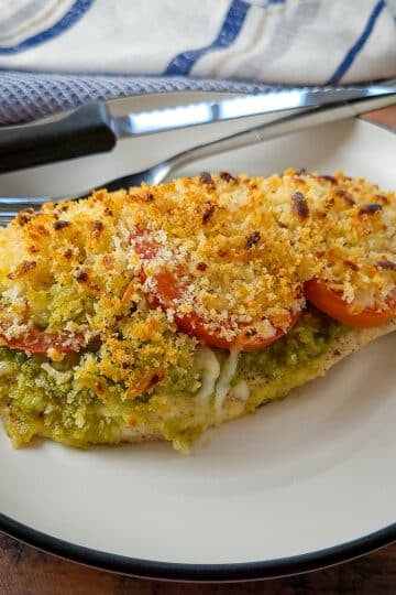baked chicken breast with pesto, tomato and cheese on a plate