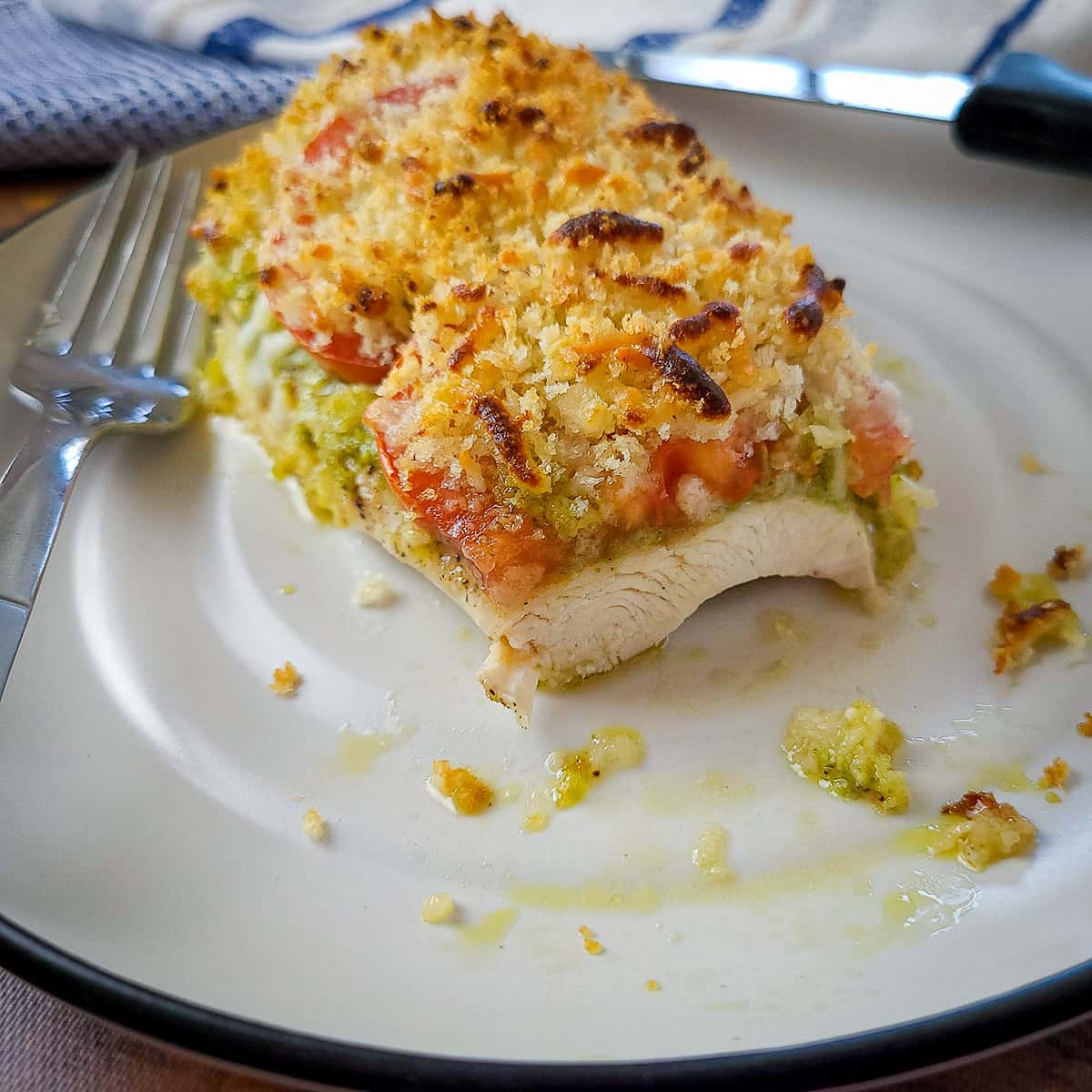 baked chicken breast with pesto, tomato and cheese on a plate