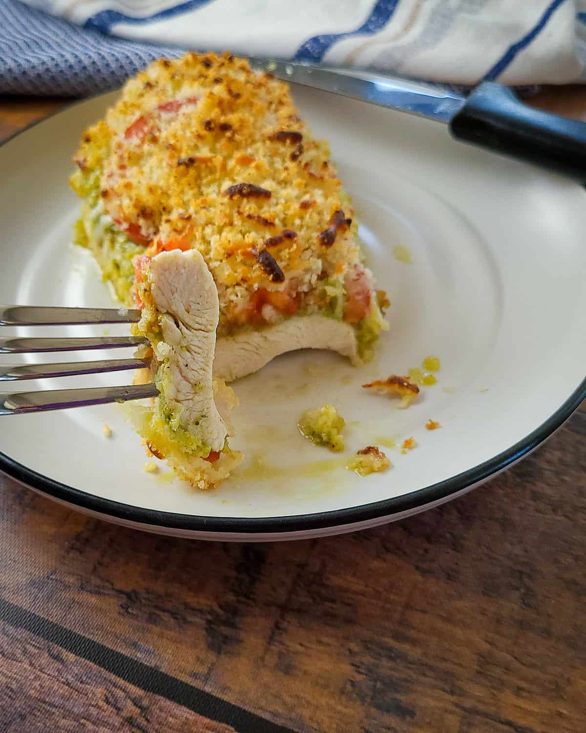 baked chicken breast with pesto, tomato and cheese on a plate
