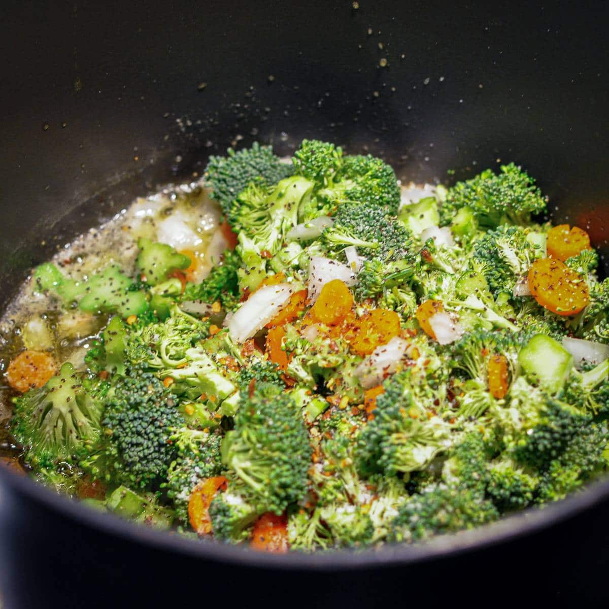 broccoli carrots and onion cooking in a large pot for soup