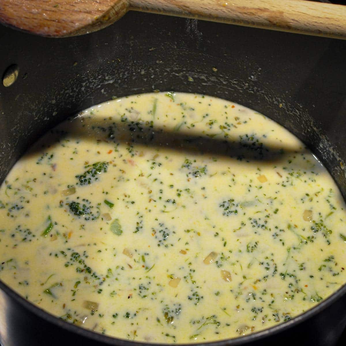 broccoli cheddar soup being cooked in a large pot