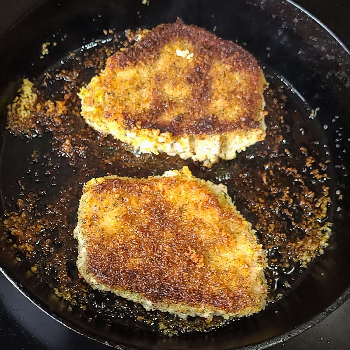 panko crusted pork chops frying in a skillet