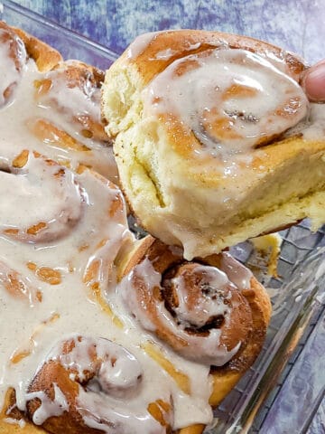 a cinnamon rolls being removed from the baking dish