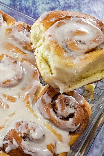 a cinnamon rolls being removed from the baking dish