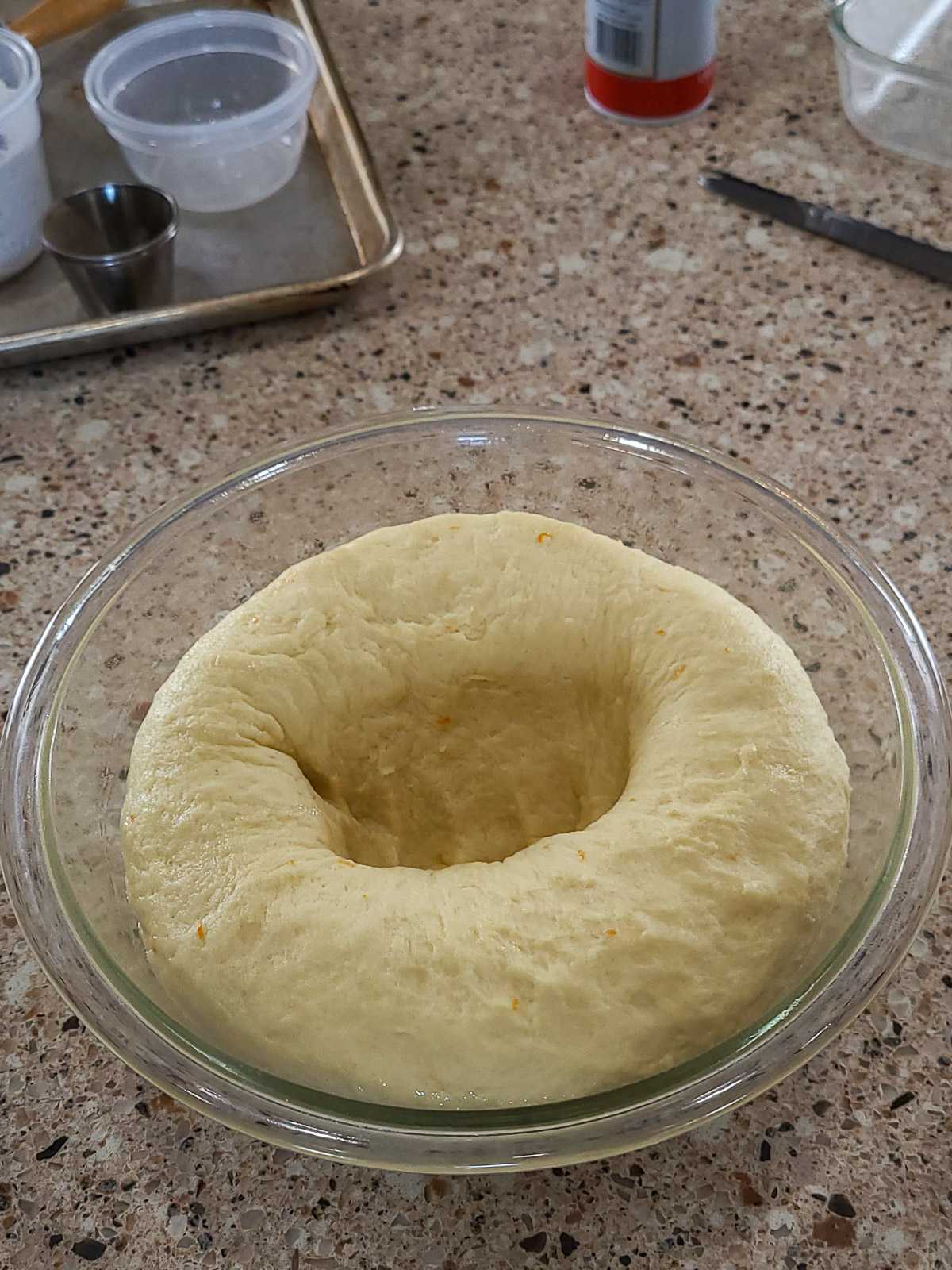 raised dough being punched down in a bowl