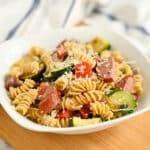 A bowl of Pasta with Veggies & Smoked Sausage featuring rotini, savory sausage, zucchini, tomatoes, and grated parmesan cheese.