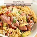 A bowl of Pasta with Veggies & Smoked Sausage featuring rotini, zucchini, tomatoes, and grated cheese, all served in a white dish.