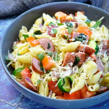 pasta with zucchini, basil, tomatoes and sausage in a gray bowl