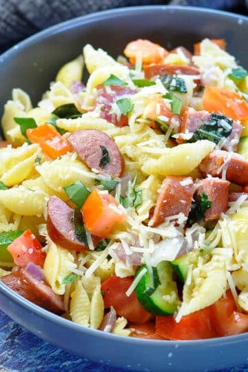 pasta with zucchini, basil, tomatoes and sausage in a gray bowl