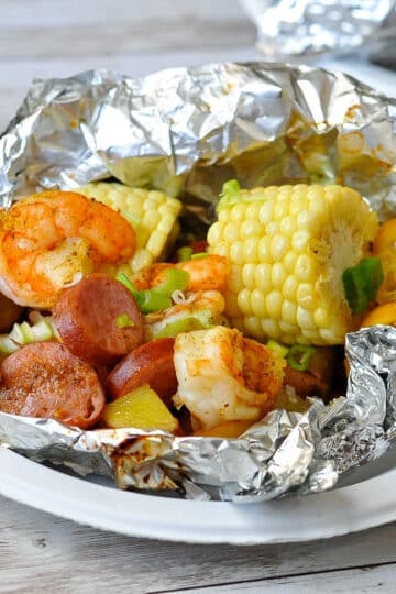 shrimp, sausage, corn, potatoes in foil ready to serve on a paper plate