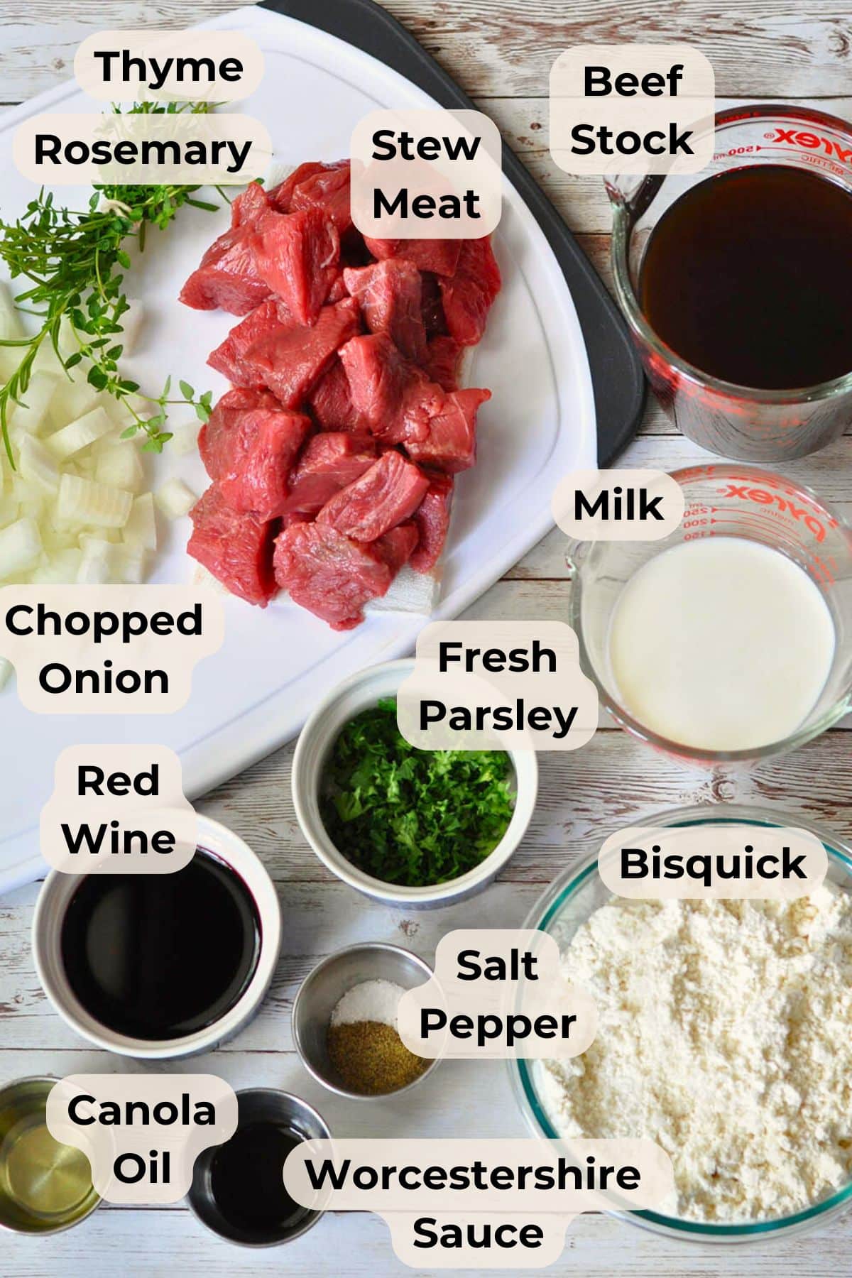 Bowls of stew meat, chopped onion, herbs, Bisquick, milk, beef stock, red wine, oil, and seasonings on a table-everything you need to make hearty Beef and Dumplings.
