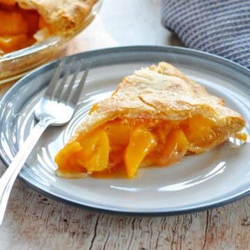 a slice of peach pie on a white and blue plate