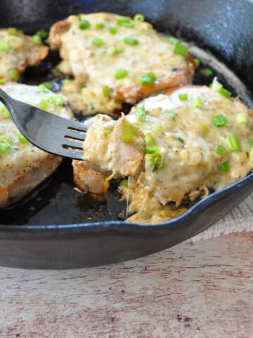pork chops covered with cheese in a cast iron skillet