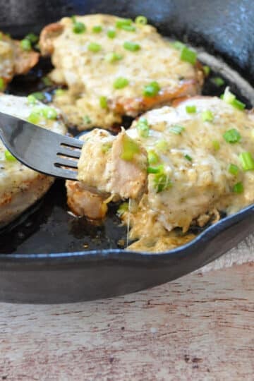 pork chops covered with cheese in a cast iron skillet