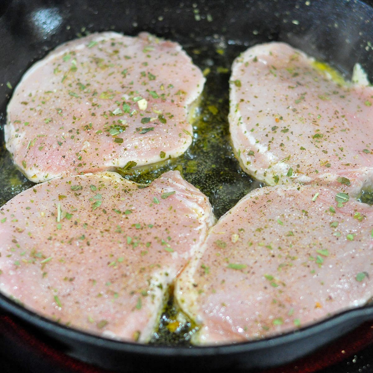 pork chops cooking in a cast iron skillet