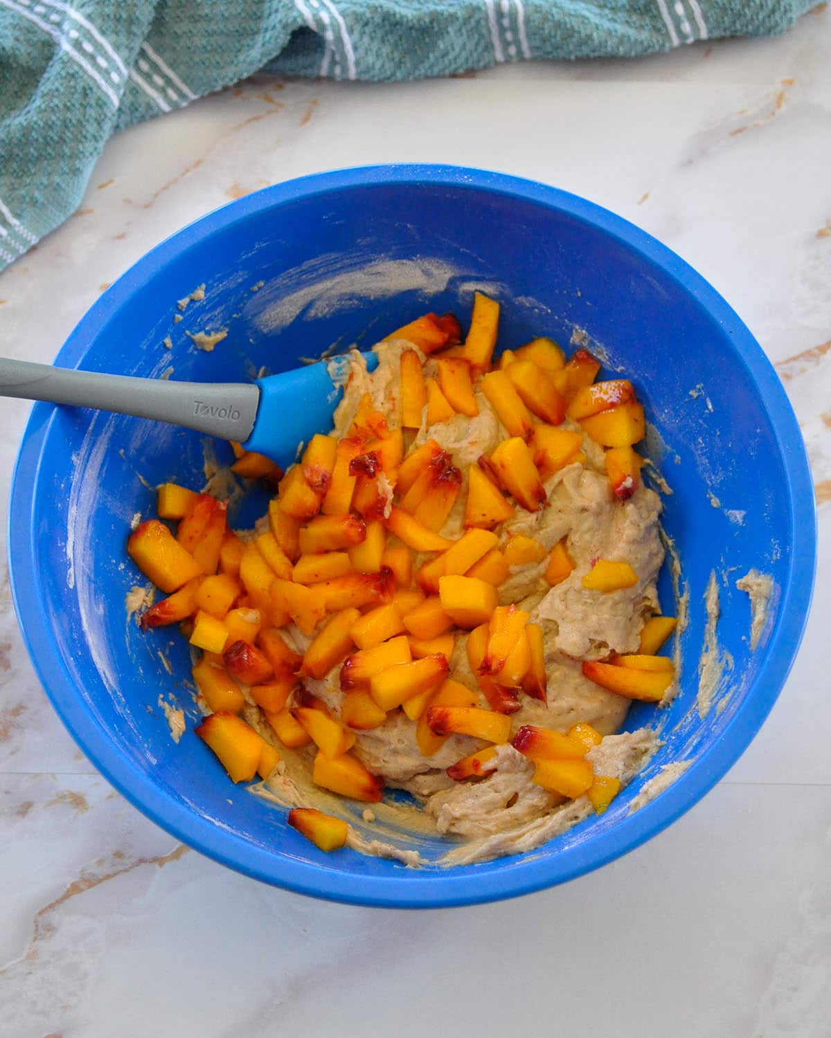 diced peaches in a blue bowl with muffin batter
