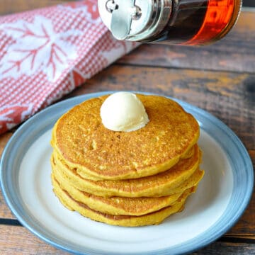a stack of pancakes topped with butter on a white and blue plate