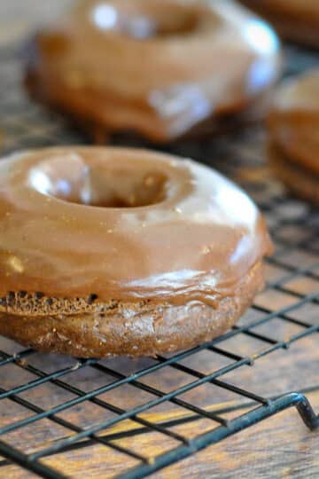 close up picture of a chocolate donut on a wire rack