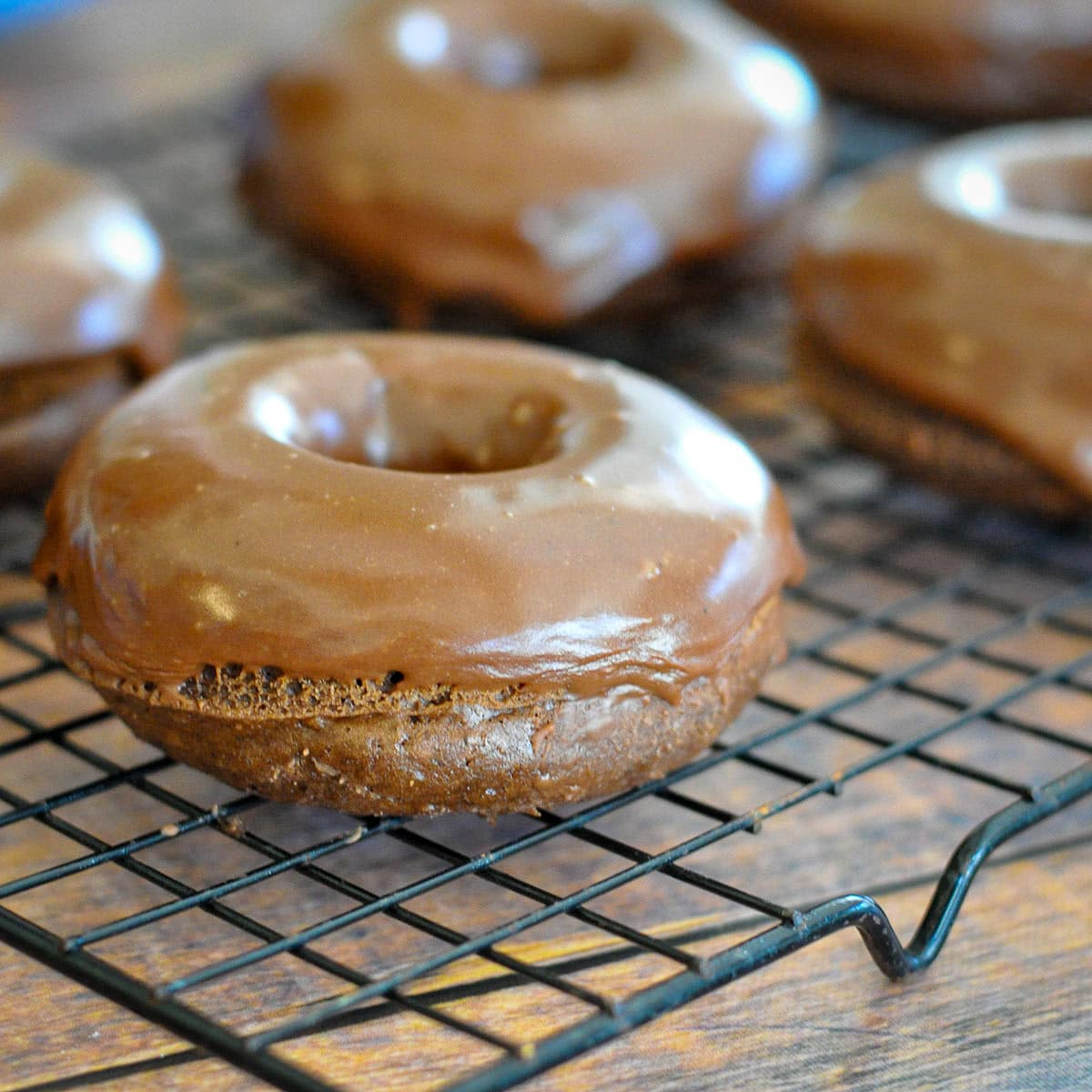 close up picture of a chocolate donut on a wire rack