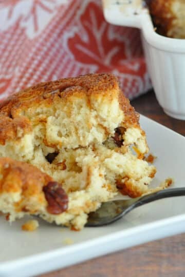 a single honey bun on a white plate with a fork