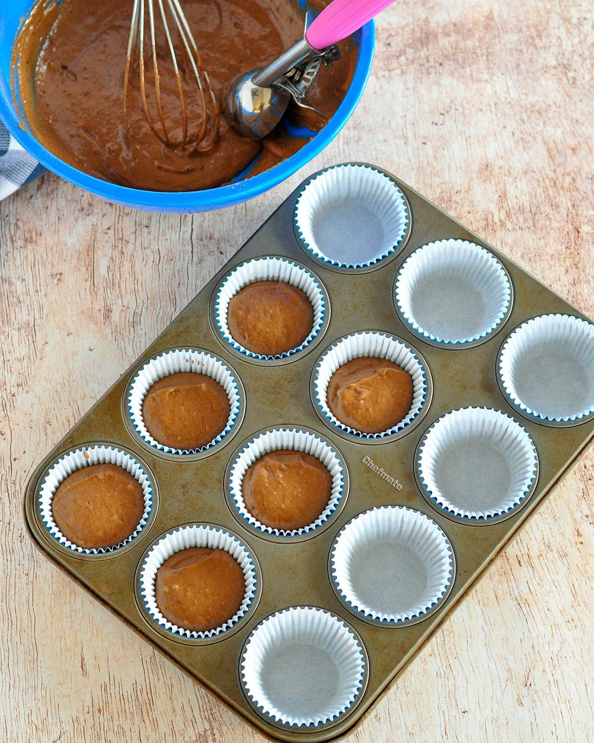 chocolate muffin batter filled in 6 out of 12 cups in a muffin tin. 