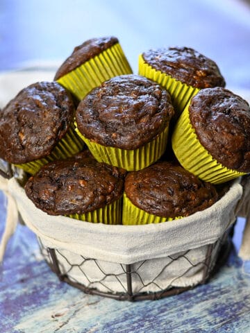 a wire basket filled with chocolate muffins with yellow muffin papers.