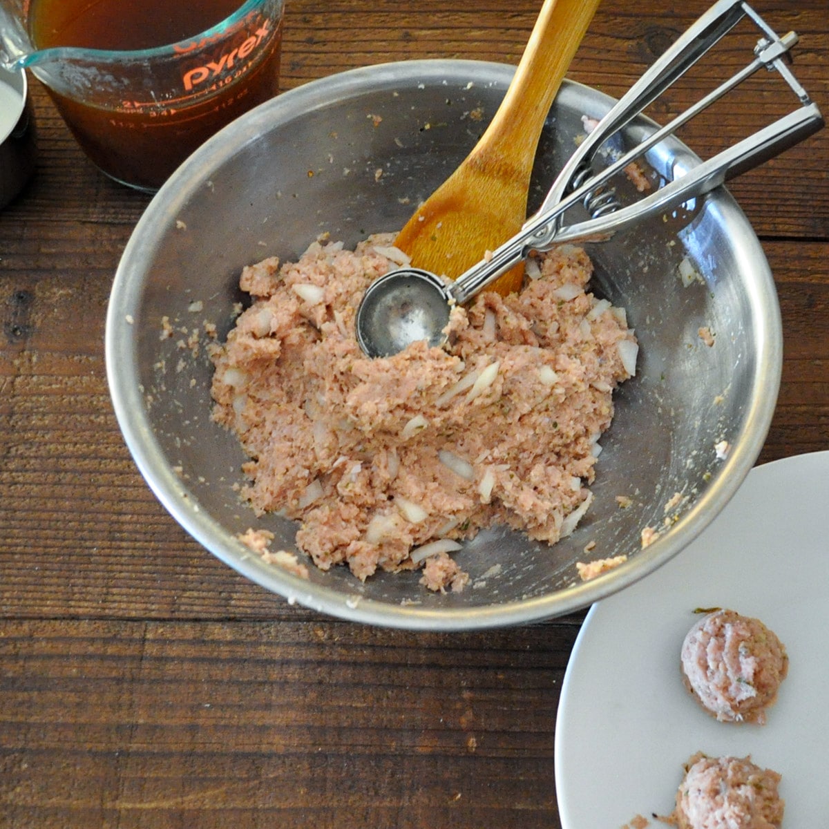 A metal bowl with raw ground turkey, onion, and spices for meatballs. 