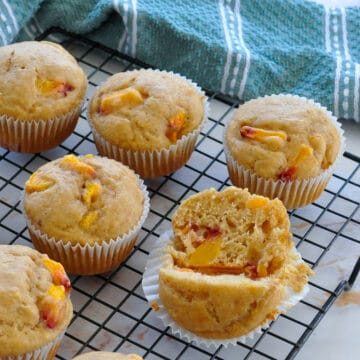 a close up of a peach muffin split open, sitting on a rack.