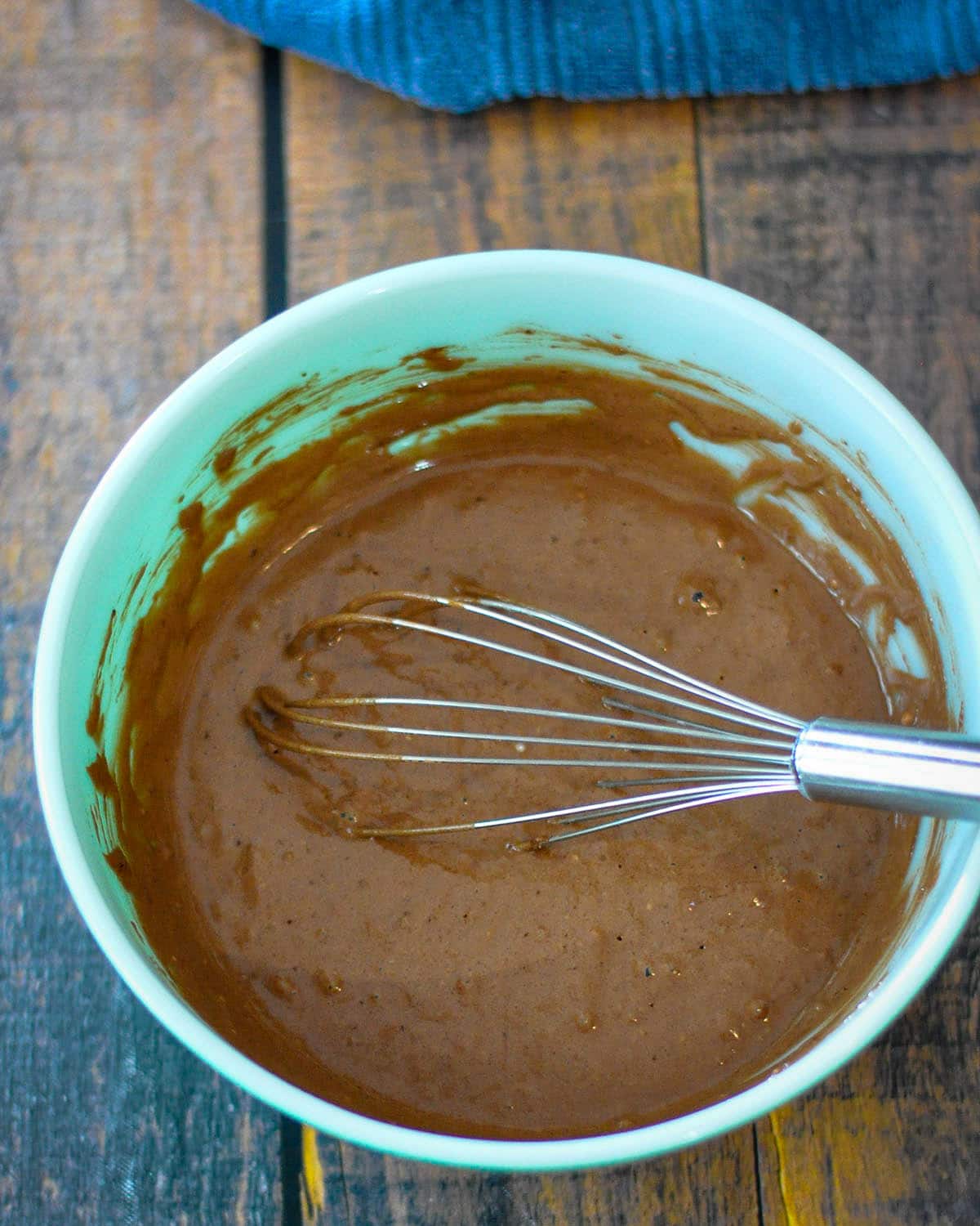 Chocolate pancake batter in a green and white bowl. 