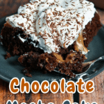A slice of mocha poke cake, adorned with cream and chocolate shavings, sits elegantly on a plate.