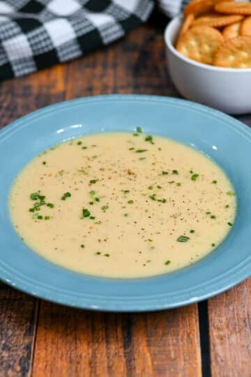 a blue bowl with onion soup next to a bowl of ritz crackers.