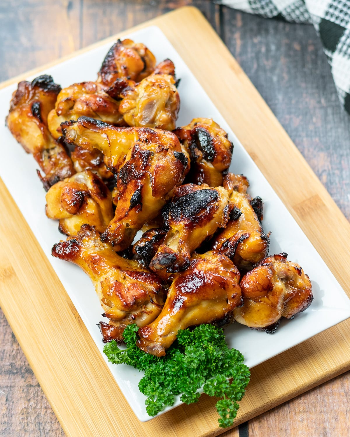 a platter of chicken wings with a side of parsley next to a black and white checkered towel.