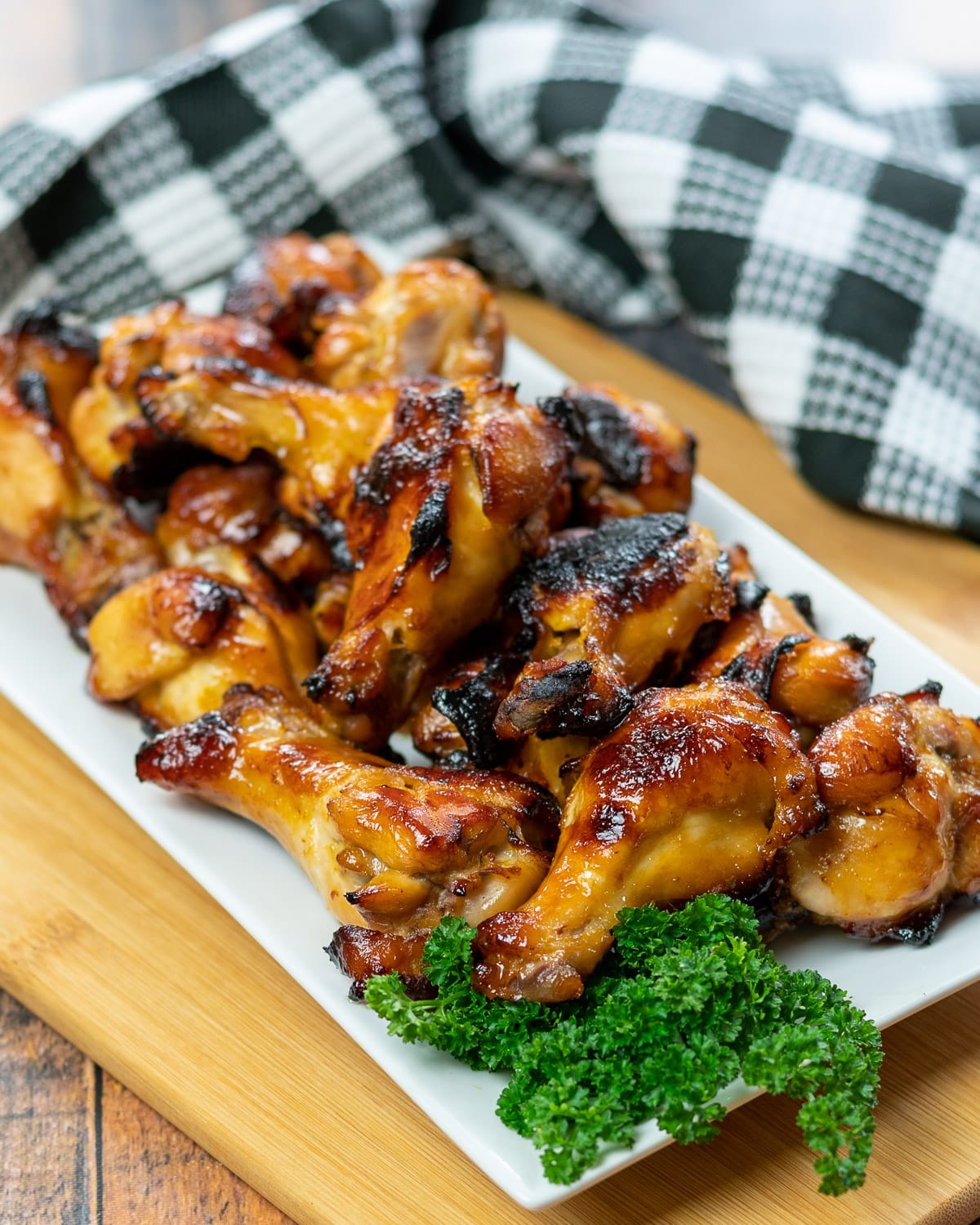 a platter of chicken wings with a side of parsley next to a black and white checkered towel.