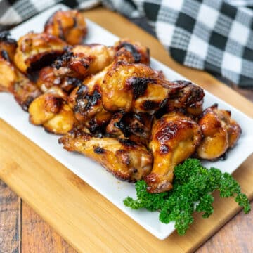 a platter of chicken wings with a side of parsley next to a black and white checkered towel.