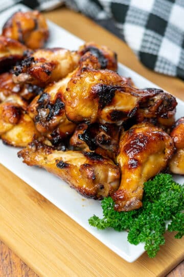 a platter of chicken wings with a side of parsley next to a black and white checkered towel.