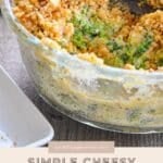 A Simple Broccoli Casserole with a cheesy crumb topping sits in a glass dish, with one generous serving already scooped out.