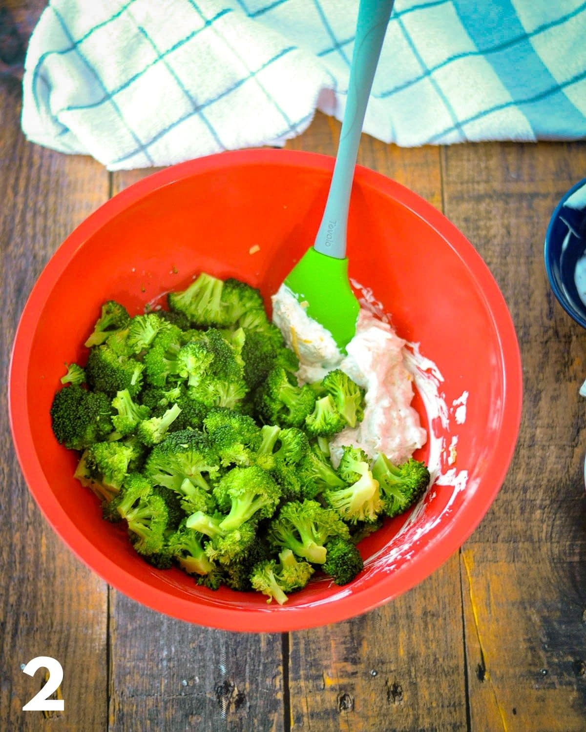 Broccoli added to seasoned sour cream and cheese in a large bowl. 