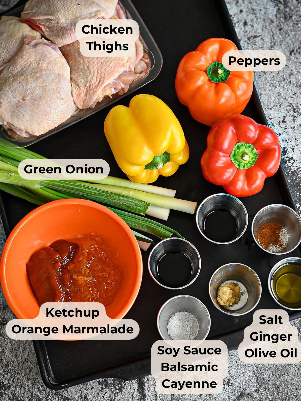 Ingredients for Baked Sweet and Sour Chicken: chicken thighs, bell peppers, green onion, sauces, seasonings, and marmalade on a tray-perfect for a homemade orange sweet and sour sauce.