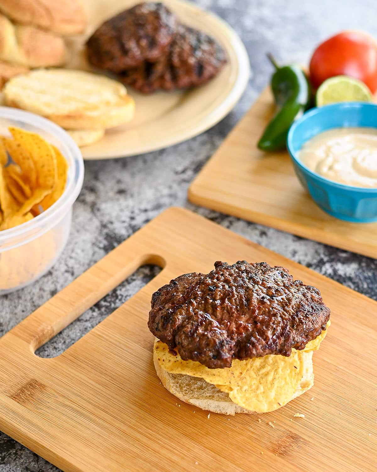 A cooked burger patty placed over tortilla chips on a bun. 