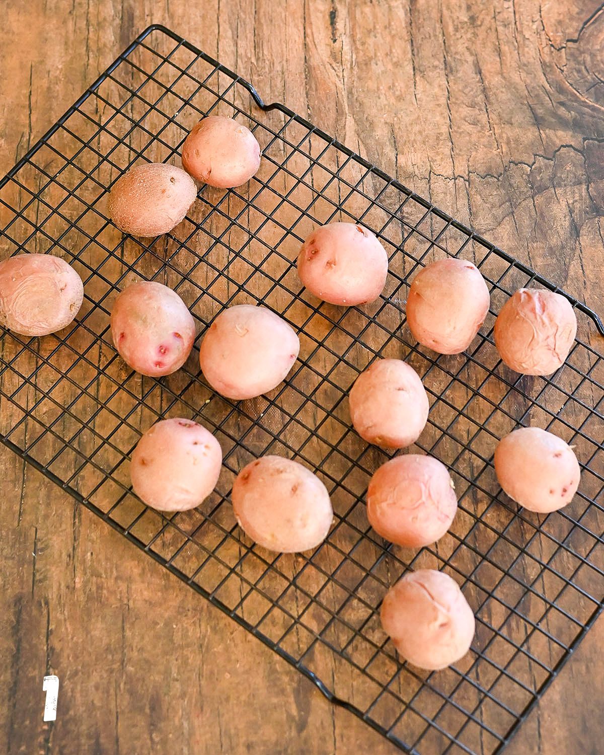 Red potatoes sitting on a black wire rack.