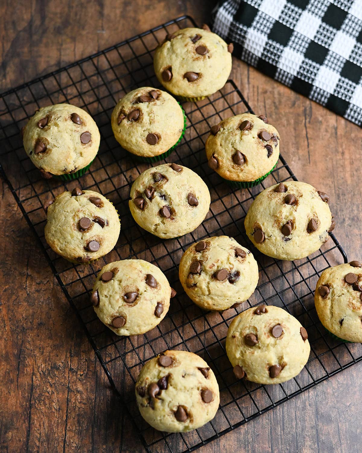 A black rack of just baked chocolate chip muffins.