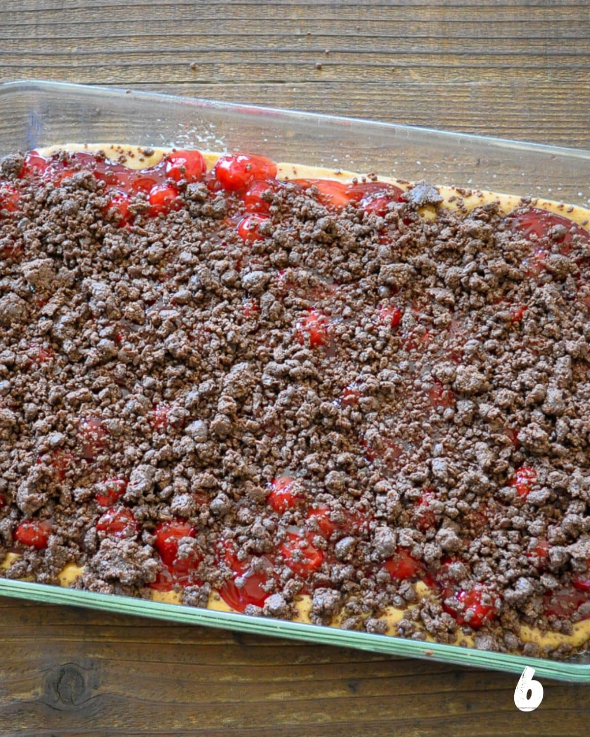 Chocolate crumb topping over cherries in a baking dish.
