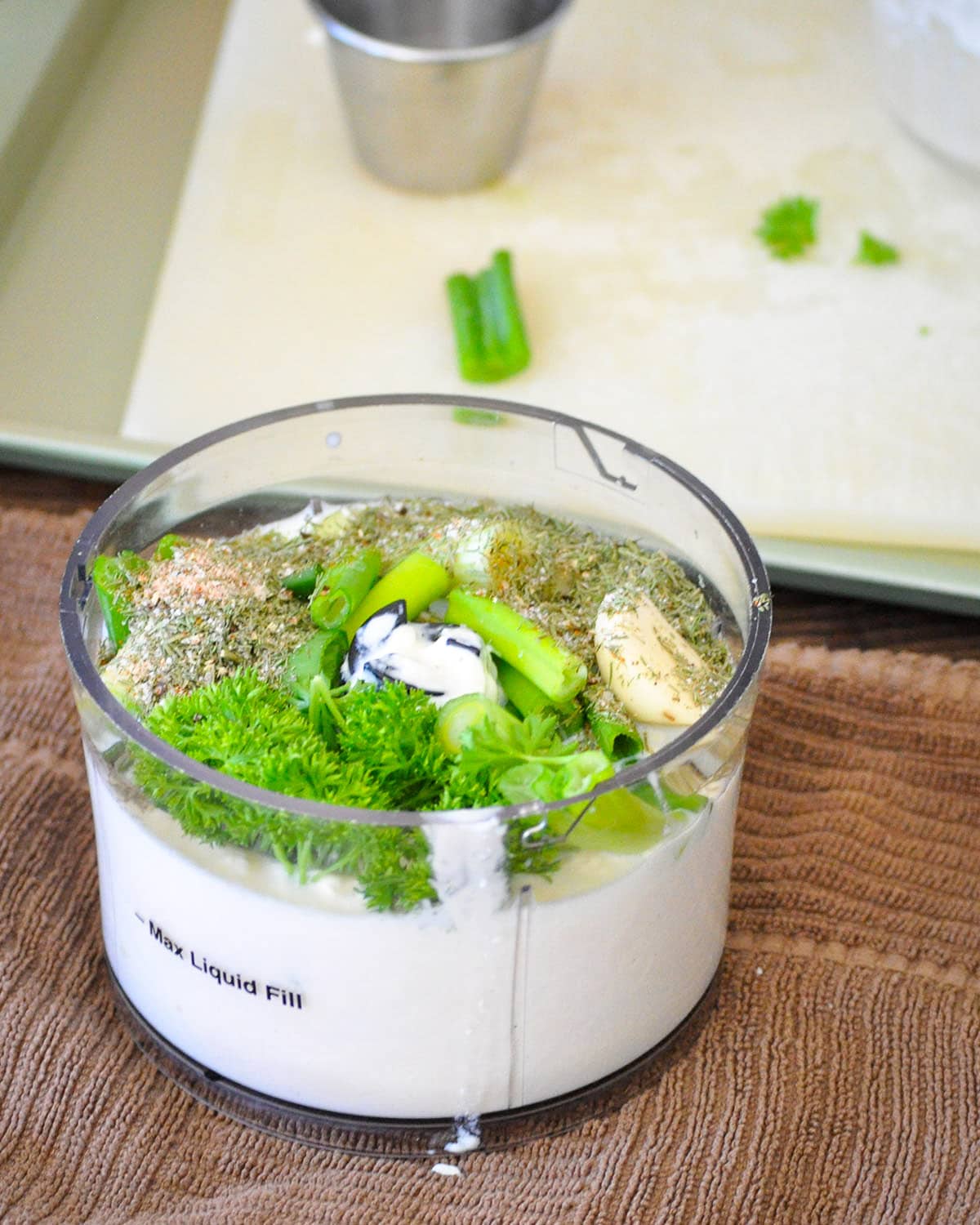 Milk, mayo, green onion, garlic, and herbs in a small food processor bowl.